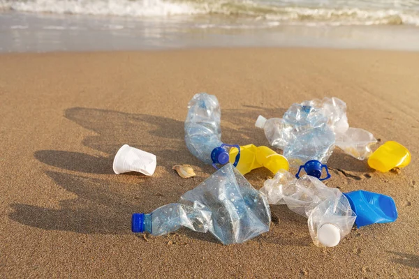 plastic products lie in a pile on the beach, by the sea, environmental problem