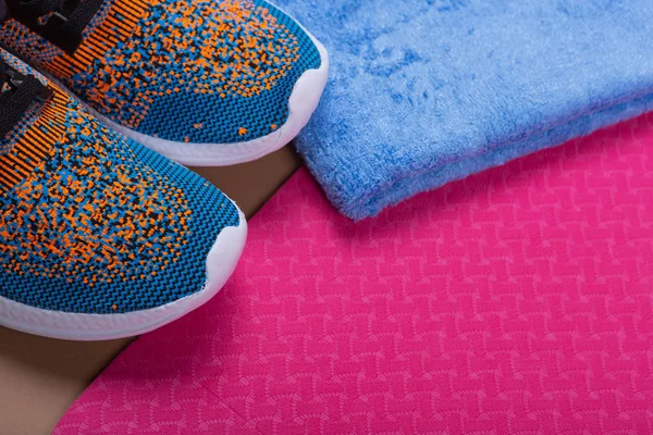 Красочные кроссовки, розовый коврик фитнес и синее полотенце, спортивная концепция — стоковое фото