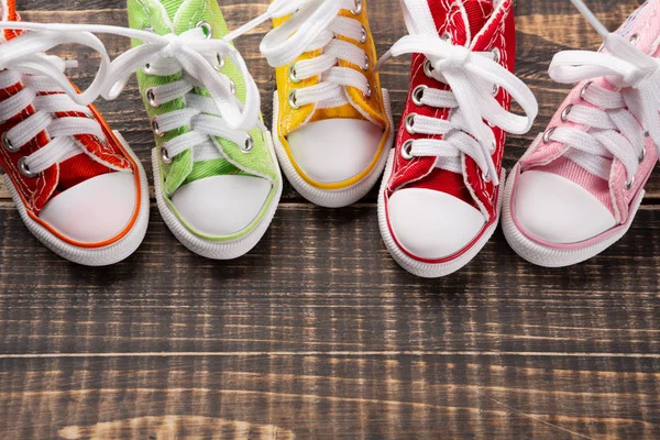 Cinco zapatillas multicolores de pie en una fila, en un tablero de madera, el concepto de verano y un estilo de vida activo —  Fotos de Stock