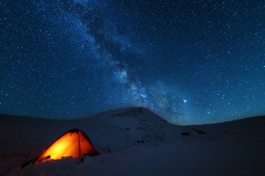 Kışın peri masalı Karpat Dağları gökyüzünde büyüleyici bir samanyolu vadilerde turist çadırları ve karlı evler