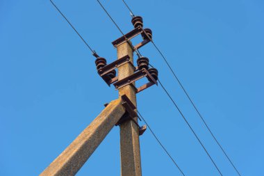 Çeşitli sırıklara ve desteklere sahip elektrik hatları, bir trafo kabininin görünümü.
