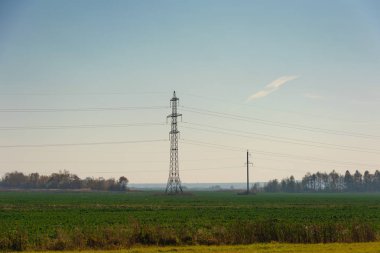 Çeşitli sırıklara ve desteklere sahip elektrik hatları, bir trafo kabininin görünümü.