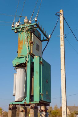 Çeşitli sırıklara ve desteklere sahip elektrik hatları, bir trafo kabininin görünümü.