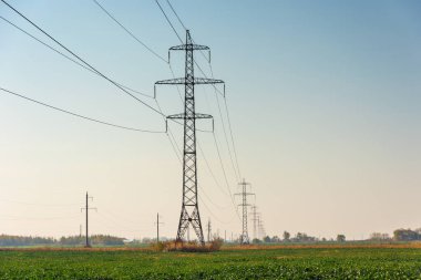 Çeşitli sırıklara ve desteklere sahip elektrik hatları, bir trafo kabininin görünümü.