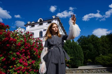 genç model parlak gün ışığı altında moda giysiler giyen süre poz