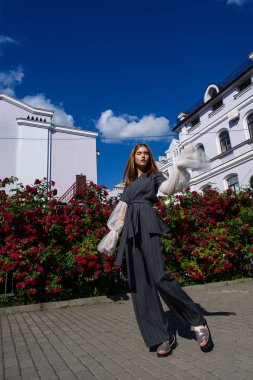 Genç redhead model parlak gün ışığı altında arka plan üzerinde çiçek açan gül ile poz