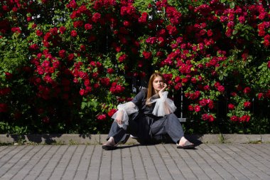 güzel genç model gül bush çiçek açan ve uzağa bakarak otururken