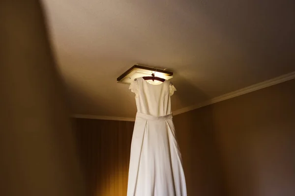 White wedding dress on hanger in room