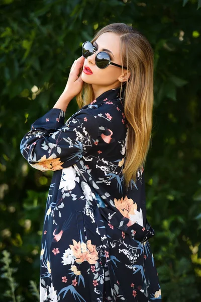 Fashion shot of woman in cape posing in green nature