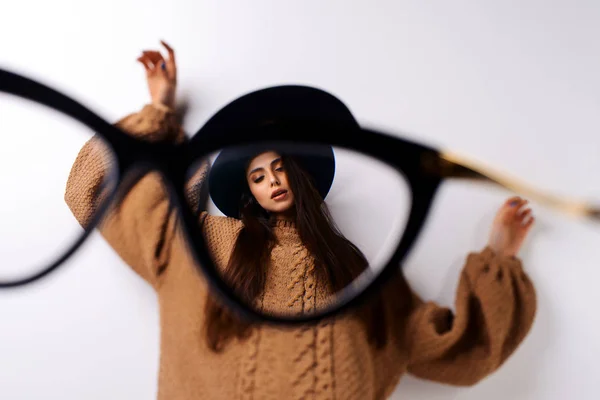 looking through glasses on sexy young beautiful brunette woman posing in hat