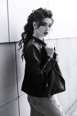 Genç, güzel esmer kadın sokakta poz veriyor.