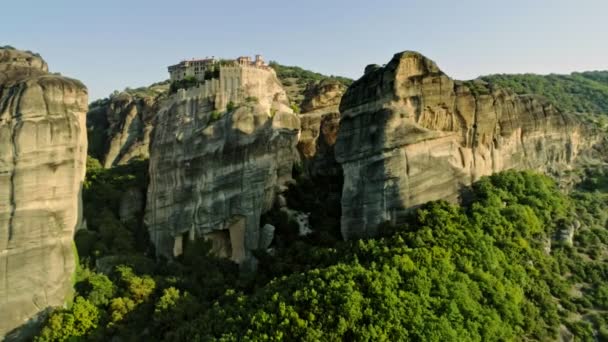 ギリシャ観光歴史場所高山に美しい自然の渓谷でメテオラは日没時緑濃い木々 に覆われた岩の頂上に修道院の複雑なショット空中パン — ストック動画