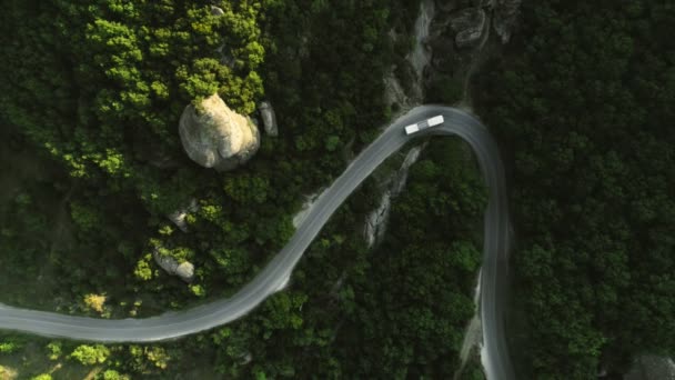 Static aerial shot top view passenger bus moving along winding asphalt road on hilly terrain — Stock Video