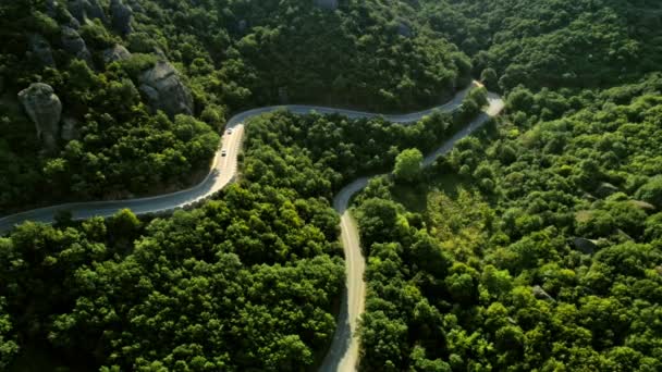 Aerial statisk sköt slingrande asfaltvägen med rörliga bilar vid solnedgången på underbara valley — Stockvideo
