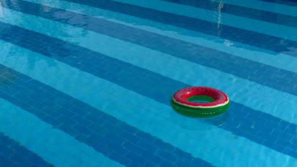 日当たりの良い夏の日に透明な青い水で空の屋外スイミング プールで浮かぶ救命浮環 — ストック動画