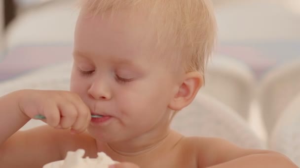 Μέτρια close-up πορτρέτο του αυτοπεποίθηση Ευρωπαϊκό μικρό παιδί που τρώει με κουτάλι παγωτού — Αρχείο Βίντεο