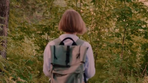 Активна молода жінка-підліток, що йде в зеленому літньому лісі в оточенні зелених дерев — стокове відео