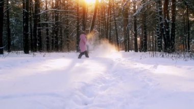 Oynak kadının kış orman günbatımında kar ile oynarken parkta dalga keyfi yerinde