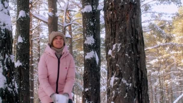 Low angle carefree smiling woman having fun tossing white clean snowflakes in forest park slowmo — Stock Video