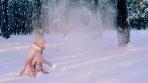 장난 활성 여자 눈 더미에 앉아서 놀고 겨울 삼림 공원에서 솜 털 눈 slowmo — 비디오