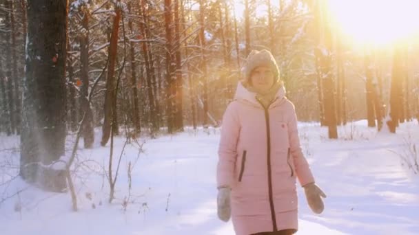 Mooie jonge gelukkige vrouw spelen met sneeuwvlokken in forest park bij zonsondergang slowmo — Stockvideo