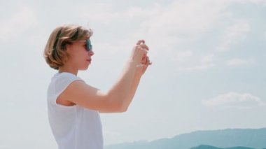 Akıllı telefon kullanarak doğa manzara fotoğraf çekmek güneş gözlüğü sevimli kadın gezgin
