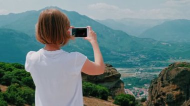 Geri görünüm kadın hipster turist akıllı telefon kullanarak inanılmaz dağ manzara fotoğraf çekmek