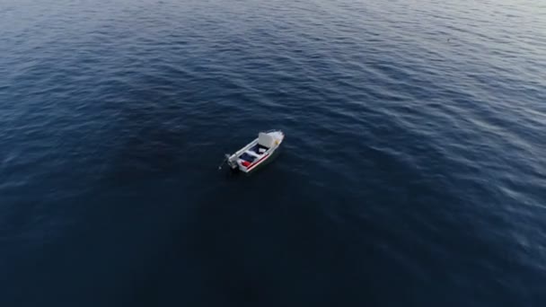 Aerial shot roterande över tom fiskebåt omgiven av mörkt blått hav vid solnedgången — Stockvideo