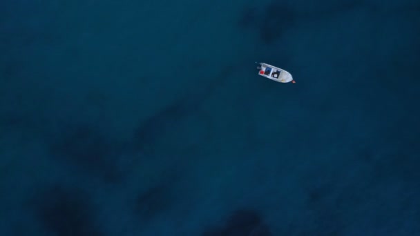 Спокій темно-синя морська вода з гладкою поверхнею повітряний постріл невеликий білий рибальський човен — стокове відео