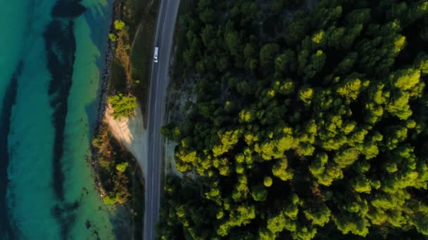 Luftaufnahme statische moderne Asphaltstraße mit fahrendem Auto direkt am Meer und dichten grünen Waldpark in Griechenland — Stockvideo