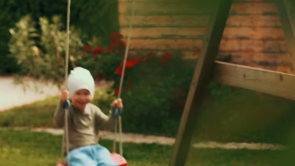 Funny little boy enjoying freedom swinging on swing full shot cute smiling baby child relaxing — Stock Video
