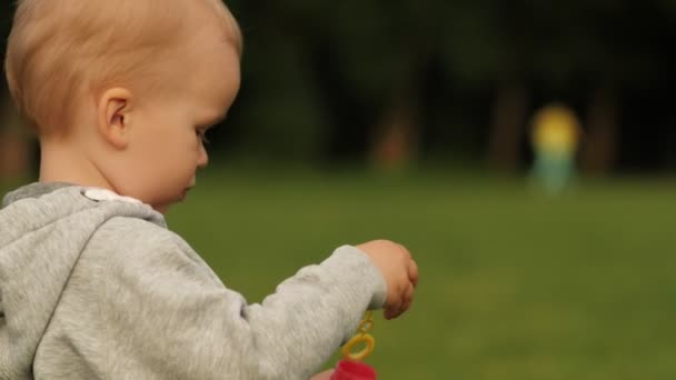 Enthousiaste kleine baby jongen blazen zeepbel met positieve emotie middelgrote close-up zijaanzicht — Stockvideo