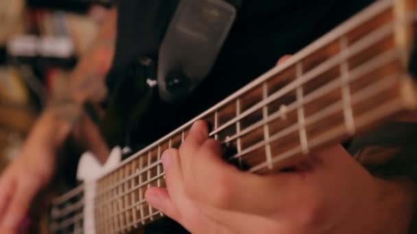 Close-up mannelijke handen van bassist spelen op elektrische basgitaar bij concert slow motion — Stockvideo