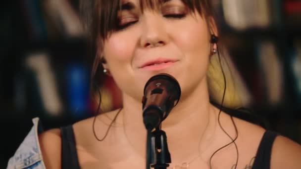 Portrait of enthusiastic young European female soloist singing on microphone at live session — Stock Video