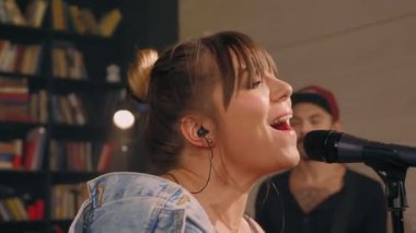 Güzel genç bayan müzik yıldızı mikrofon rock performansıyla duygusal olarak şarkı söylüyor.