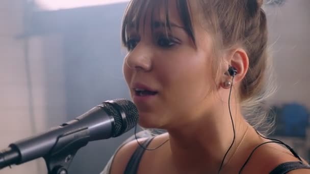 Medium close-up portrait of attractive young soloist woman singer emotionally singing on microphone — Stock Video