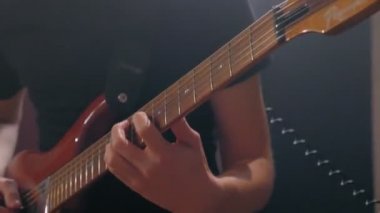 Elektro gitar çalan profesyonel gitaristin yakın çekim erkek elleri canlı seansın keyfini çıkarıyor