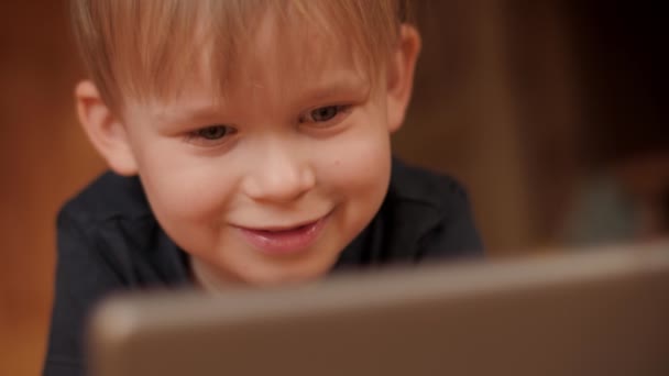 Cara de regocijo bebé niño relajarse en casa viendo entretenimiento en la tableta de PC — Vídeos de Stock