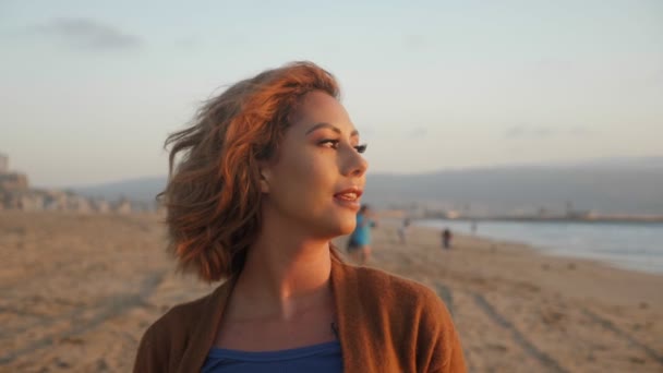 Sorridente bella giovane donna latina in cappello in posa sulla spiaggia al tramonto medio da vicino — Video Stock