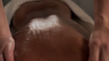 Bronzlaşmış kadın derisi masajı yapan iki masörün yakın çekim elleri güzellik salonundaki sırt kası masajı.