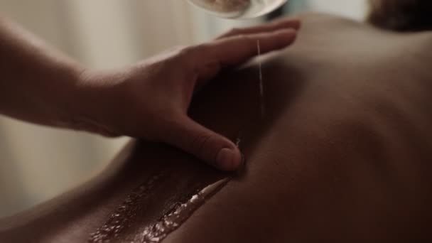 Mani massaggiatore primo piano versando olio massaggiante sulla schiena femminile preparandosi al massaggio rilassante — Video Stock