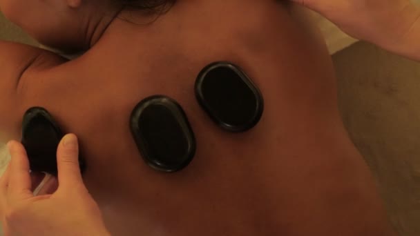 Close-up procedure van hete stenen massage in spa schoonheidssalon bovenaanzicht ontspannen rugspieren — Stockvideo