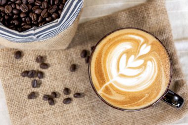 Arka planda kahve çekirdeği olan sıcak kahve fincanı.