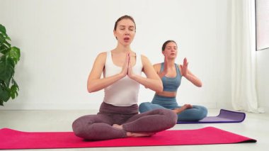 Yoga ve meditasyon yapan iki kadın, nefeslerine konsantre olurken sükunet ve farkındalığı somutlaştırıyor, rahatlama ve rahatlamayı teşvik ederken iç benlikleriyle derin bir bağ kuruyorlar.