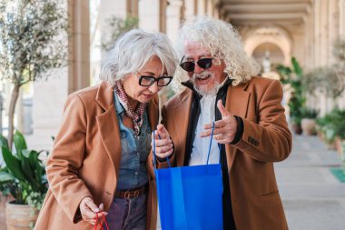Eğlenceli bir alışveriş deneyimi yaşayan neşeli yaşlı çift bulgularını paylaşırken ve hayatın neşesini keşfederken birbirlerine eşlik ederken ve değerli anılar yaratırken