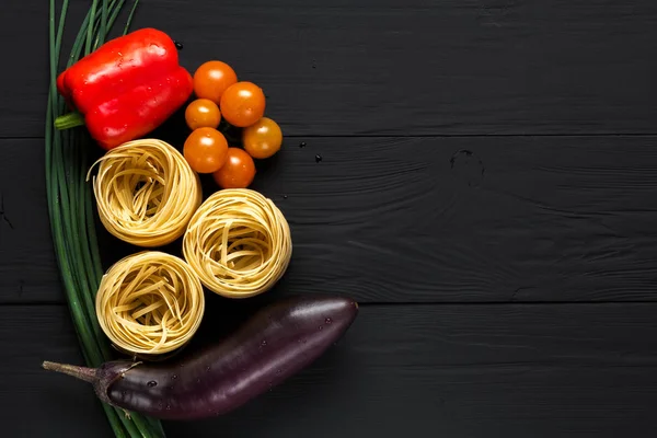 pasta and vegetables on black background, copyspace