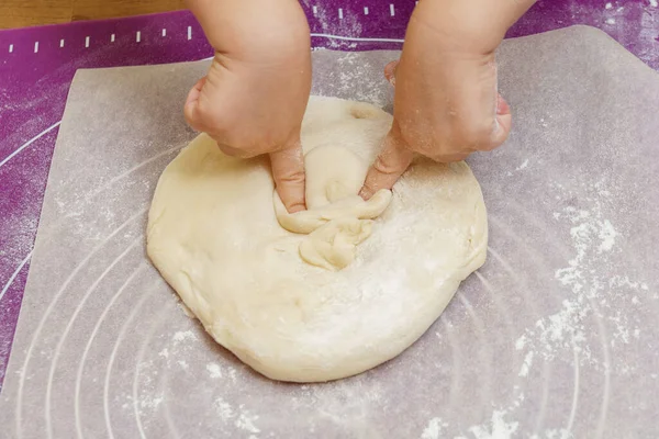 Children\'s hands knead the pizza dough. on a silicone mat