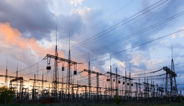 Güneş doğarken ya da batarken renkli bir gökyüzüne karşı yüksek voltajlı elektrik hatlarından oluşan bir siluet..