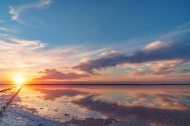 Ahşap direkler, Ukrayna 'da mavi gökyüzü ve tuzlu gölün pembe sularında tuz çıkarmak için bir kapı şeklinde eskimiş..