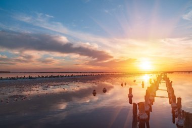 Pembe tuz gölünde gün batımı, pembe tuz çıkarmak için eski bir maden. Tuzla kaplanmış tahta çiviler..